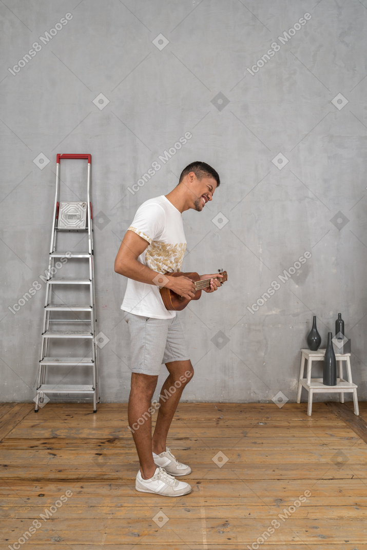 Vista laterale di un uomo che suona felicemente l'ukulele