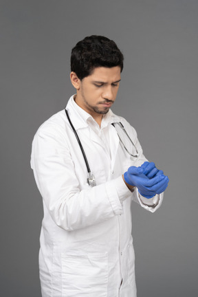 Doctor putting on blue gloves