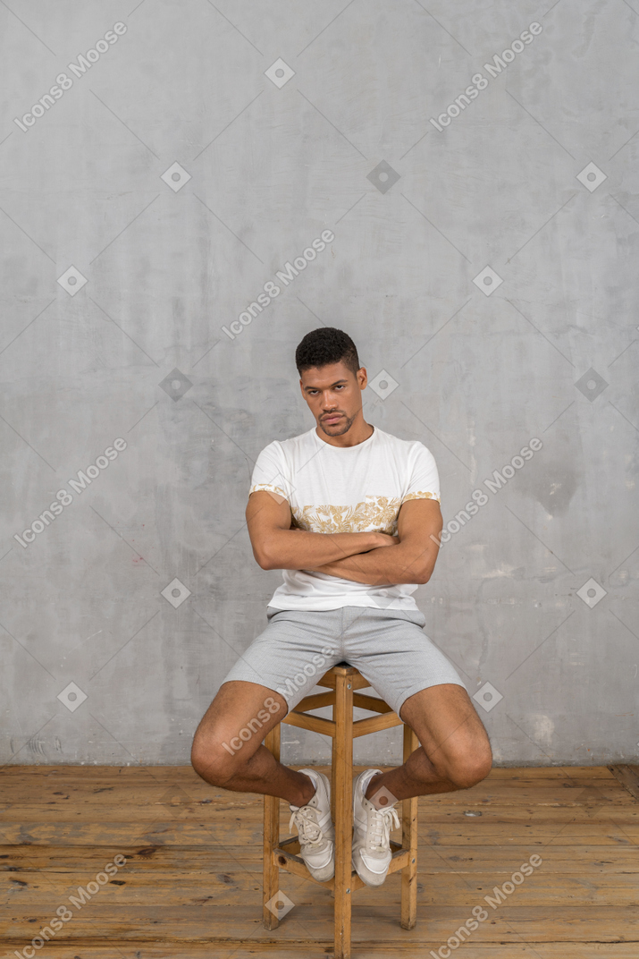 Young man sitting and looking from under his brows