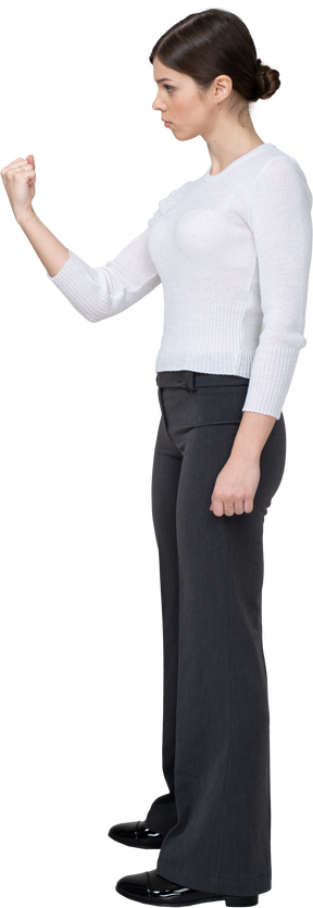 Three-quarter back view of a strict young woman in office clothing showing fist
