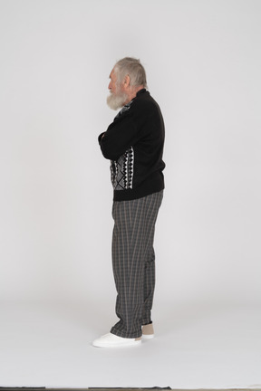 Side view of elderly man standing with arms crossed