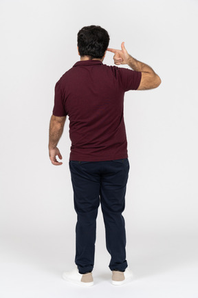 Back view of a man pointing a finger gun at head