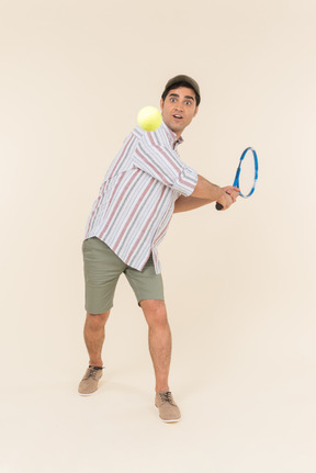 Young caucasian guy throwing ball with tennis racket