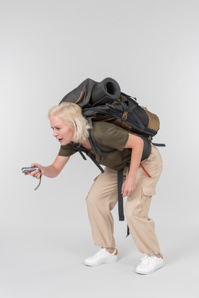 Carrying backpack mature female tourist using dictaphone