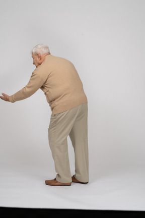 Vista trasera de un anciano con ropa informal haciendo un gesto de bienvenida