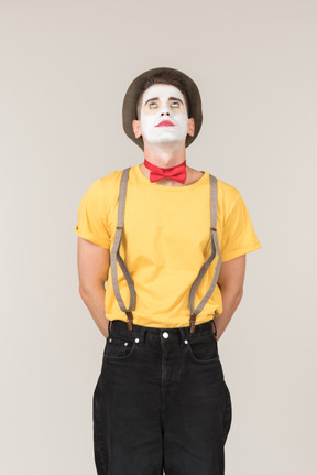 Male clown standing with hands behind his back and rolling his eyes up