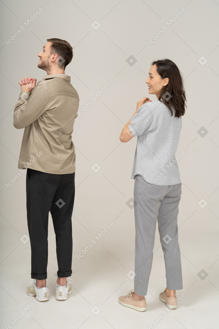 Three-quarter back view of young couple expressing please gesture