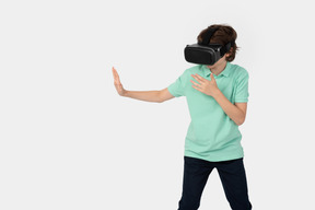 Boy in virtual reality headset going to touch something imaginary