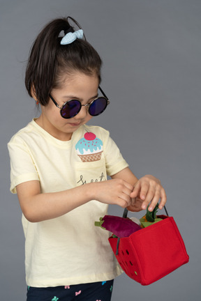 Close-up of a little girl in sunglasses holding a shopping basket