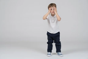 Sad little boy covering his face