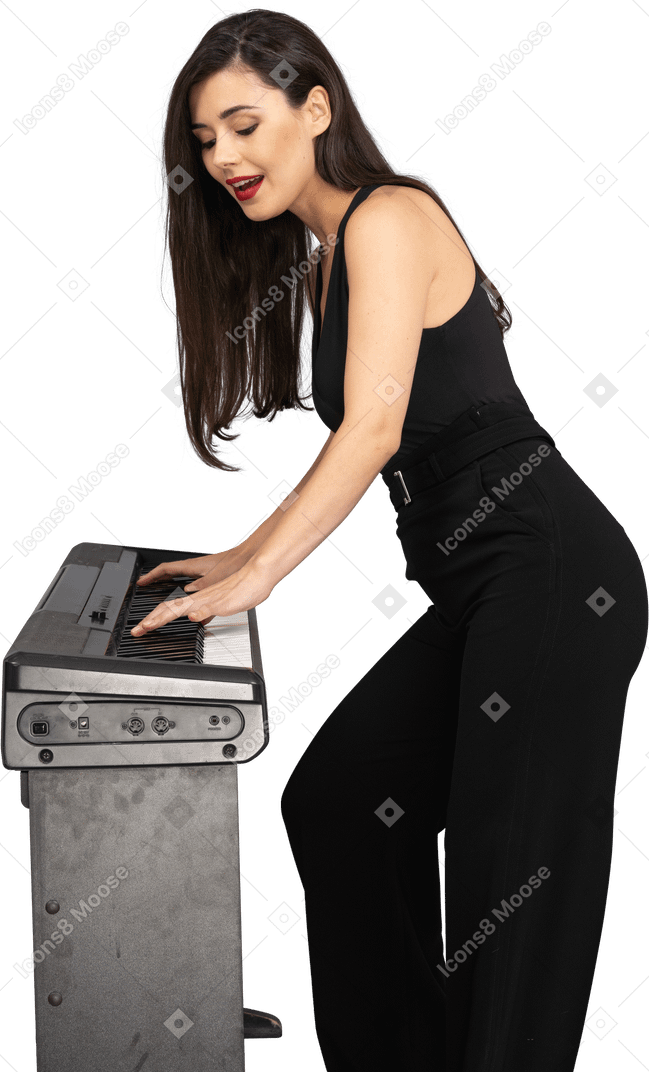 Vue latérale d'une jeune femme en costume noir jouant du piano