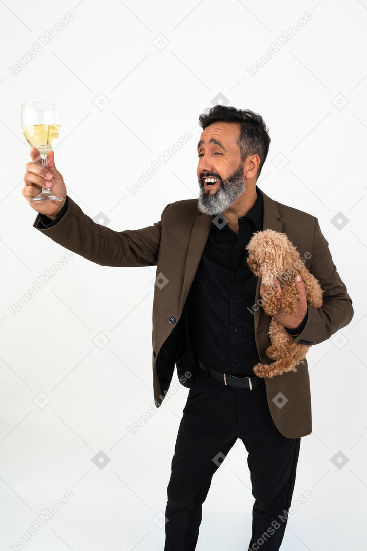 Cheerful mature man holding a dog and saying 'cheers'