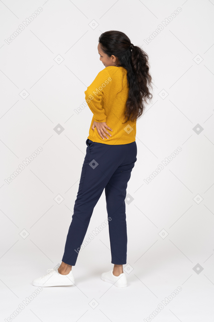 Side view of a girl in casual clothes posing with hand on hip