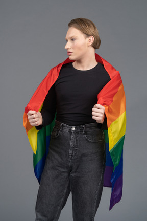 Pessoa não binária envolta em uma bandeira de arco-íris