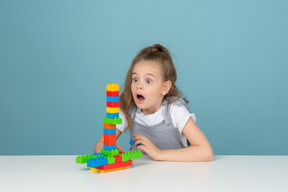 A shocked little girl playing with building blocks