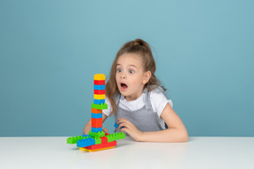 Una niña sorprendida jugando con bloques de construcción.