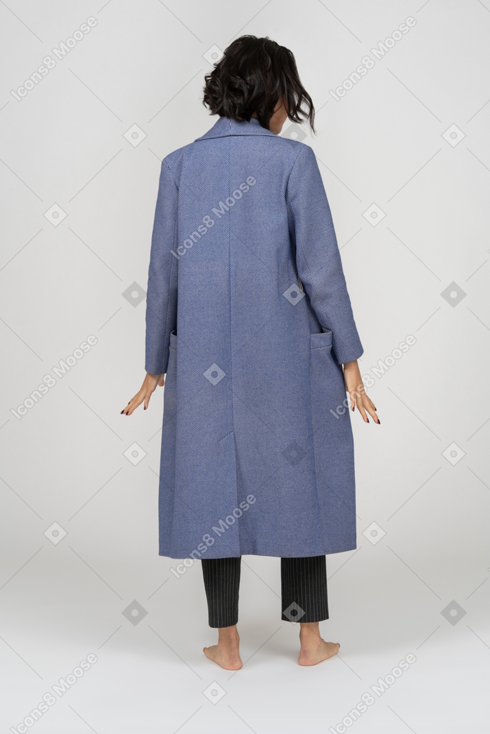 Vue arrière d'une femme en manteau debout avec les bras sur les côtés