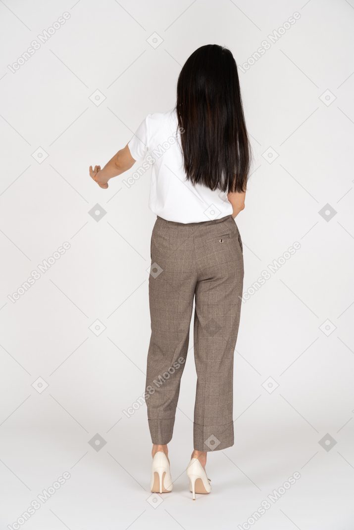 Vista traseira de uma jovem de calça esticando a mão