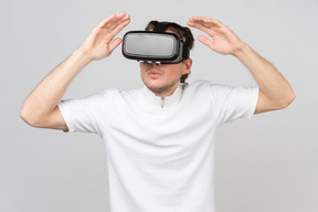 Young man in virtual reality headset standing with his hands raised