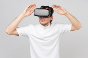 Junger mann mit virtual-reality-headset steht mit erhobenen händen