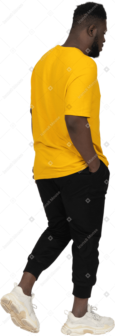 노란 티셔츠를 입은 짙은 피부의 젊은 남자의 3/4 뒷모습
