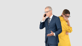 A man in a suit and tie talking on a cell phone next to a woman