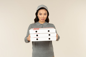 Young asian pizza delivery girl holding pizza boxes