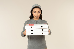 Joven asiática repartidor de pizza con cajas de pizza