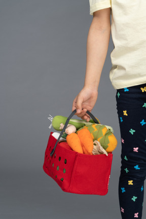 Kleines mädchen, das einkaufstasche mit spielzeug gefüllt trägt