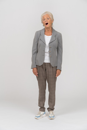 Front view of a sleepy old lady in suit yawning