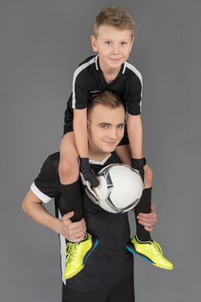 Close-up of a football player holding little boy on his neck