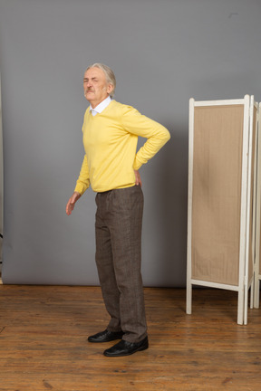 Side view of an old man with a strong back pain