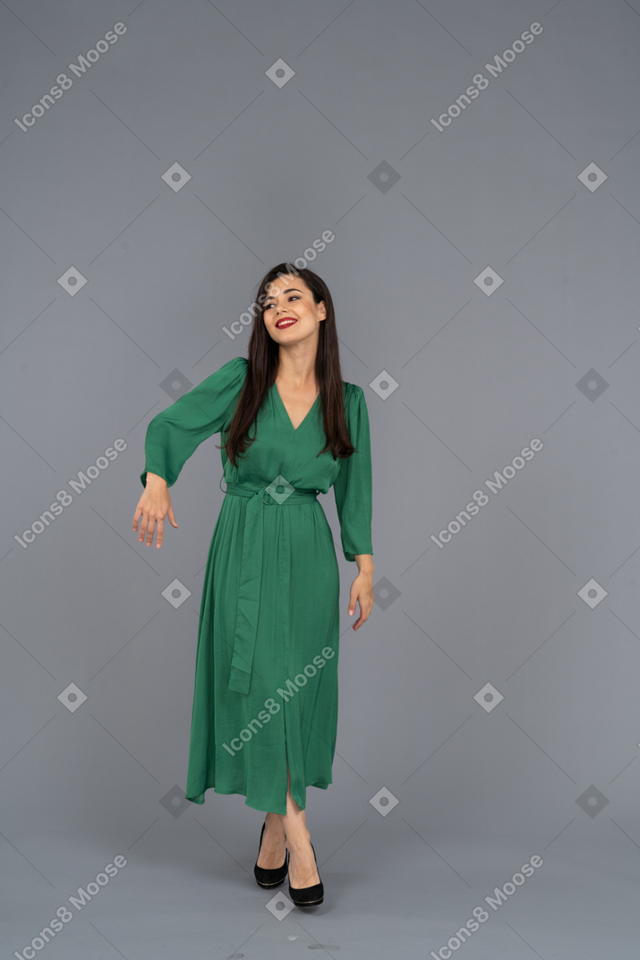 Вид спереди приветствующей молодой леди в зеленом платье