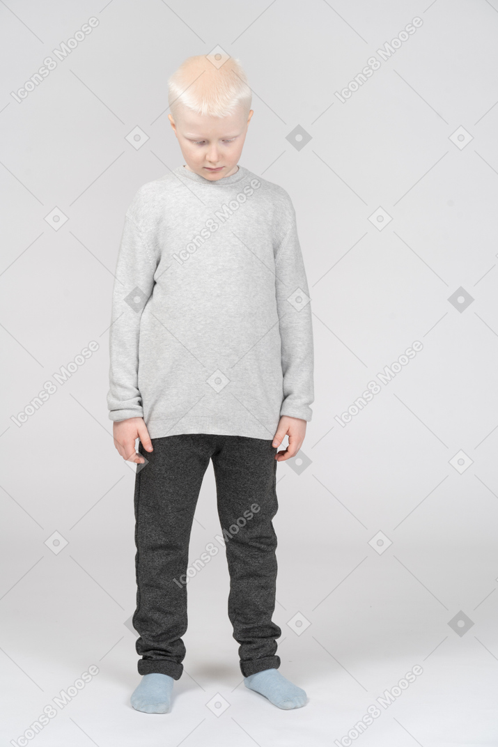 Little boy standing with closed eyes and head down