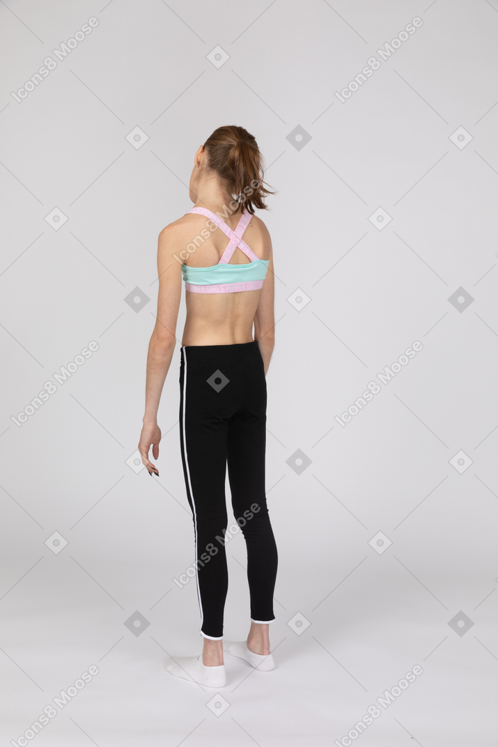 Vista posterior de una jovencita en ropa deportiva mirando hacia abajo