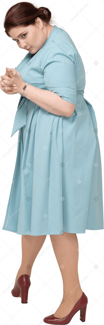 Vista laterale di una donna in abito blu che mostra la pistola con le dita