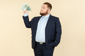 A plus-size man in a black costume with dollar bills in his hands