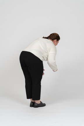 Vista laterale di una donna di taglie forti in abiti casual che si china