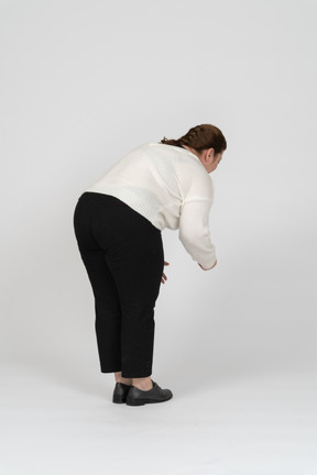 Side view of a plus size woman in casual clothes bending down