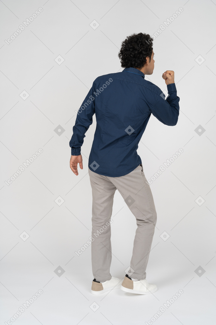 Вид сзади человека в повседневной одежде, показывающего кулак