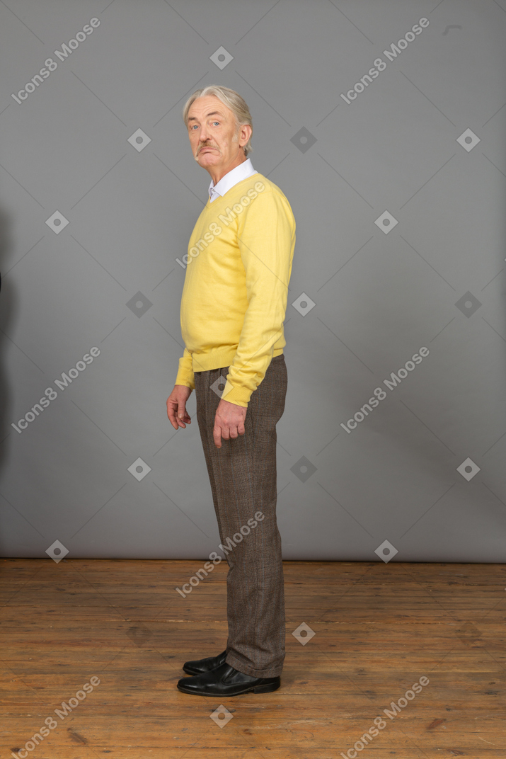 Side view of a displeased old man looking at camera