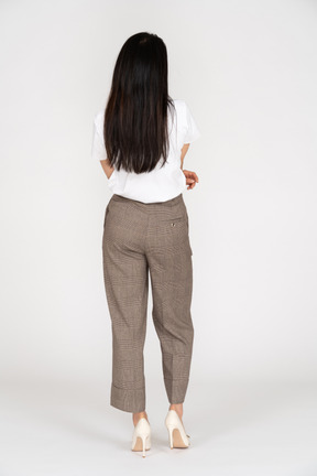Vista posteriore di una giovane donna in calzoni e t-shirt attraversando le mani