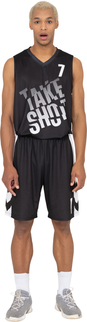 Vista frontale di un giovane giocatore di basket maschile scioccato in piedi immobile