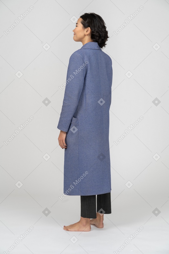 Вид сзади улыбающейся женщины в синем пальто