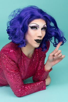 Nahaufnahme einer drag queen, die lächelt, während sie locken um den finger wickelt