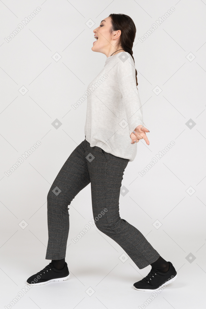 Happy young woman walking sideways with her hands wide open