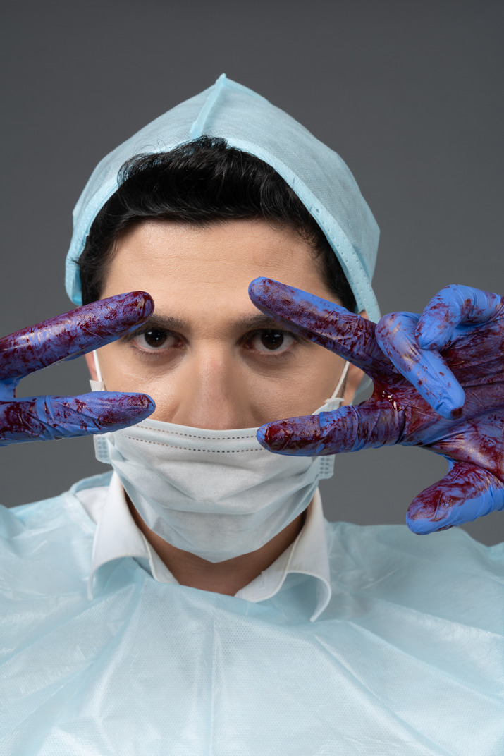 Doctor showing peace sign with bloody hands