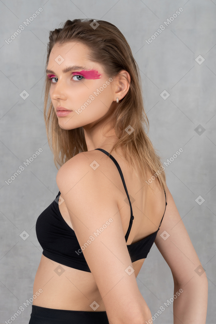 Seitenansicht einer jungen frau mit kräftigem augen-make-up, die arme hinter dem rücken hält