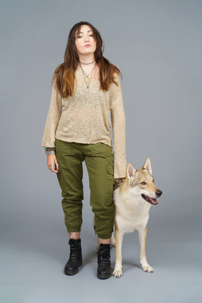 Pleine longueur d'un maître féminin debout près de son chien et regardant la caméra