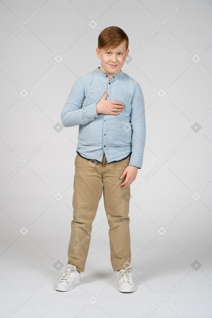 一个手放在胸前摆姿势的可爱男孩的前视图